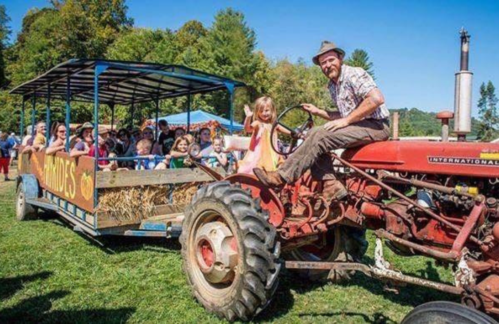 Kids in a wagon pulled by a tractor on a bluebird fall day