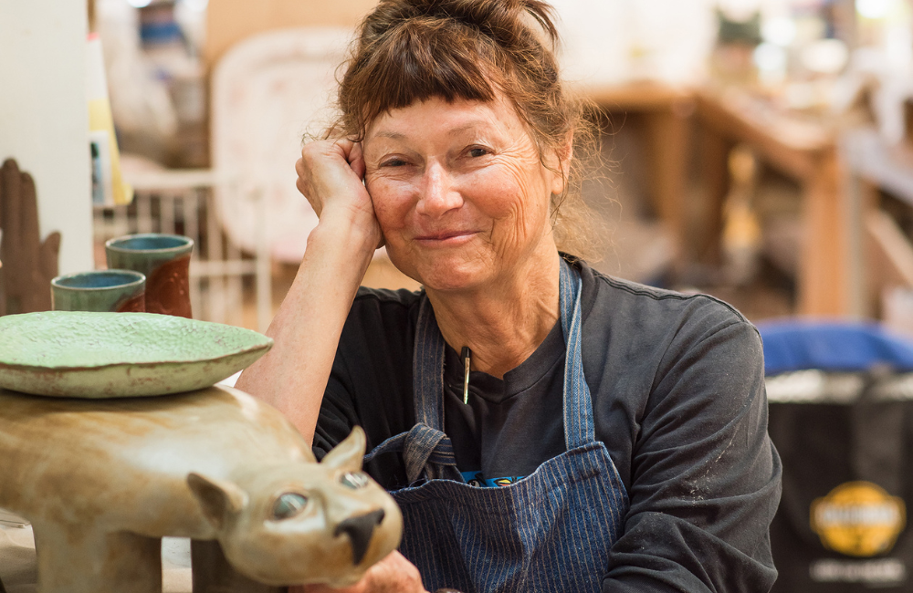 clay artist posing with plates and bowls