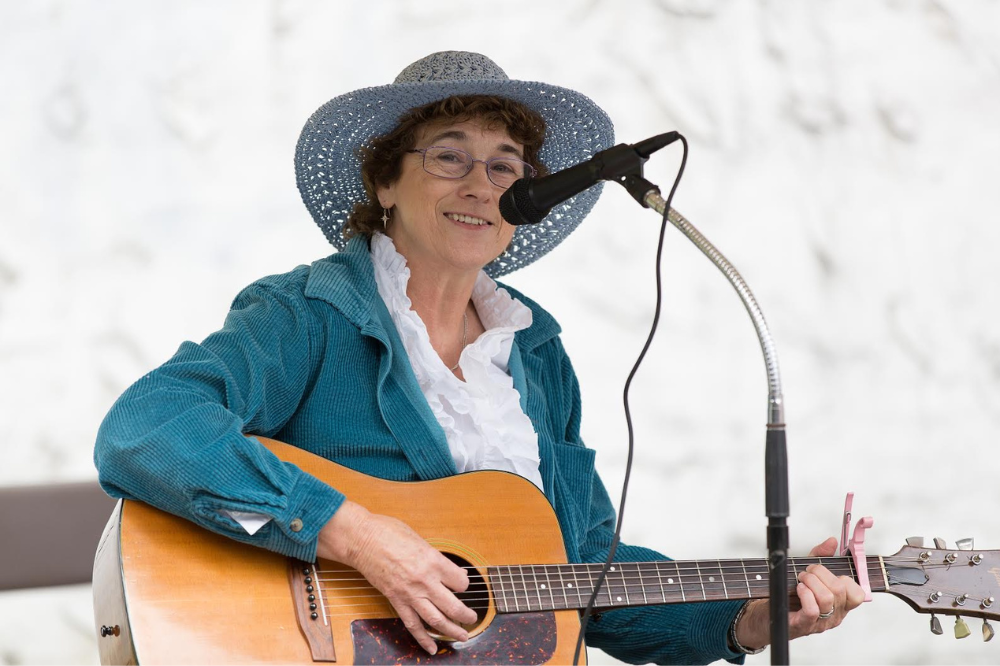 A woman singing and playing a guitar