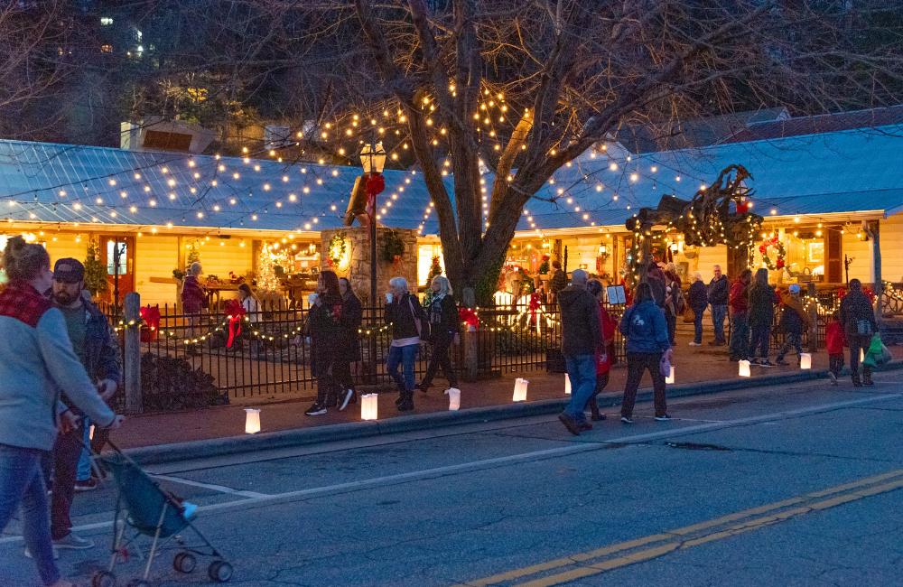 Luminaries line the street and holiday lights dazzle as people walk in downtown Dillsboro