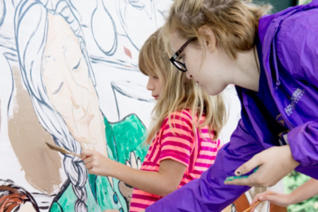 Teen and younger children painting a mural